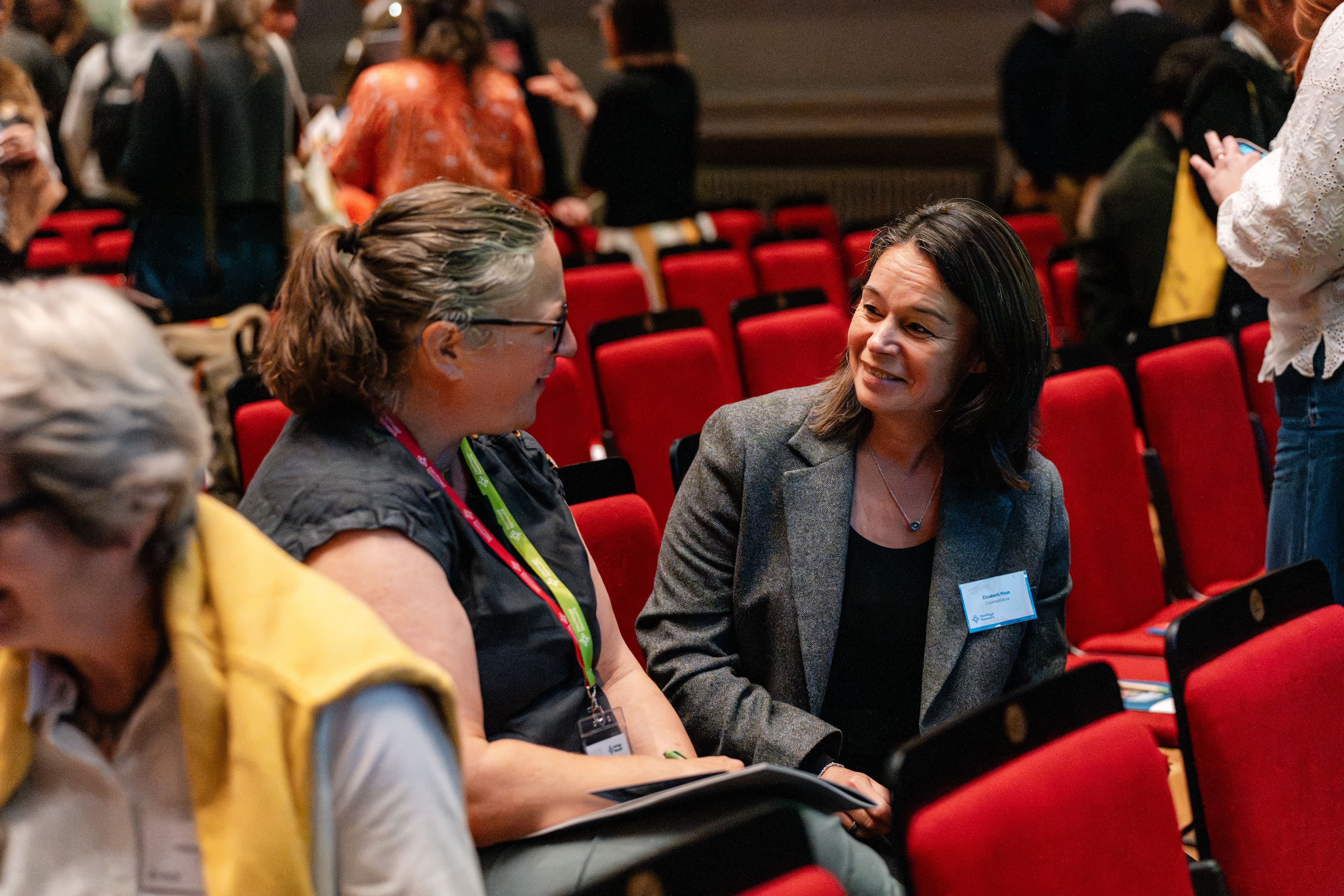 Two people having a conversation whilst sat down in an auditorium