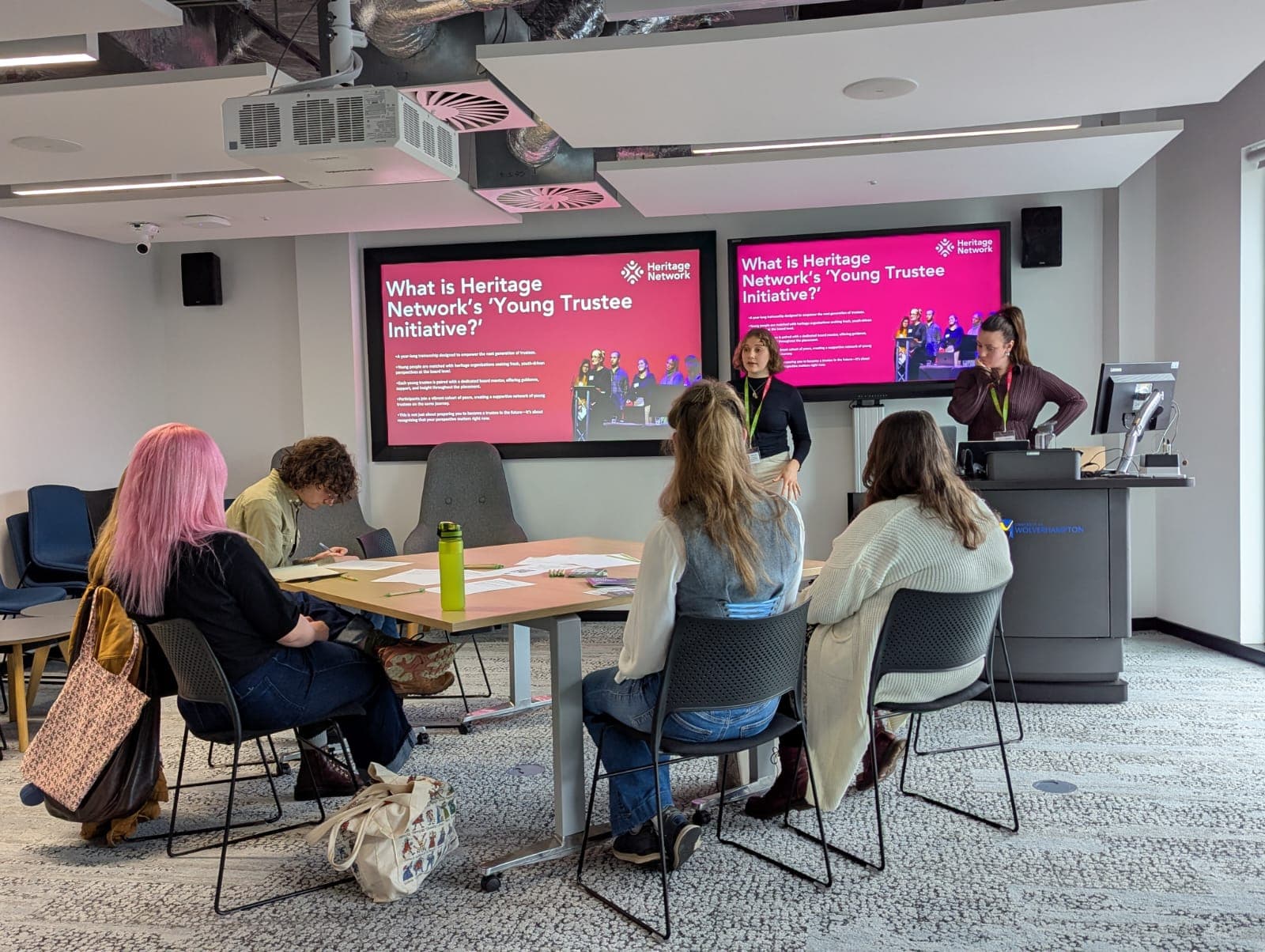 A group of young people sit watching a presentation about young trustees.