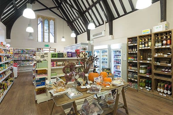 A community shop within a historic church. Shelves and tables are filled with food and drink produce.