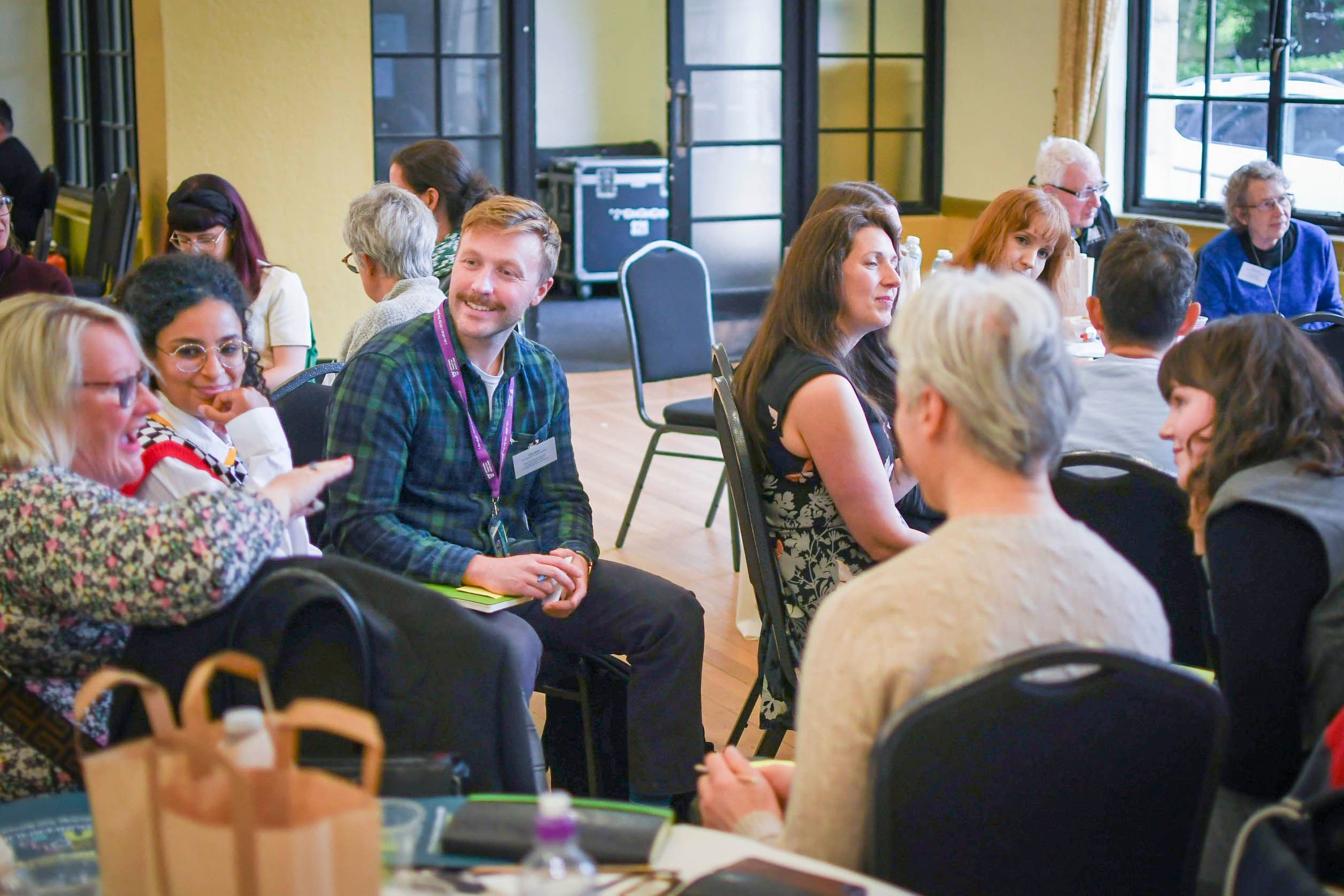 A group of people sat around chatting and smiling.