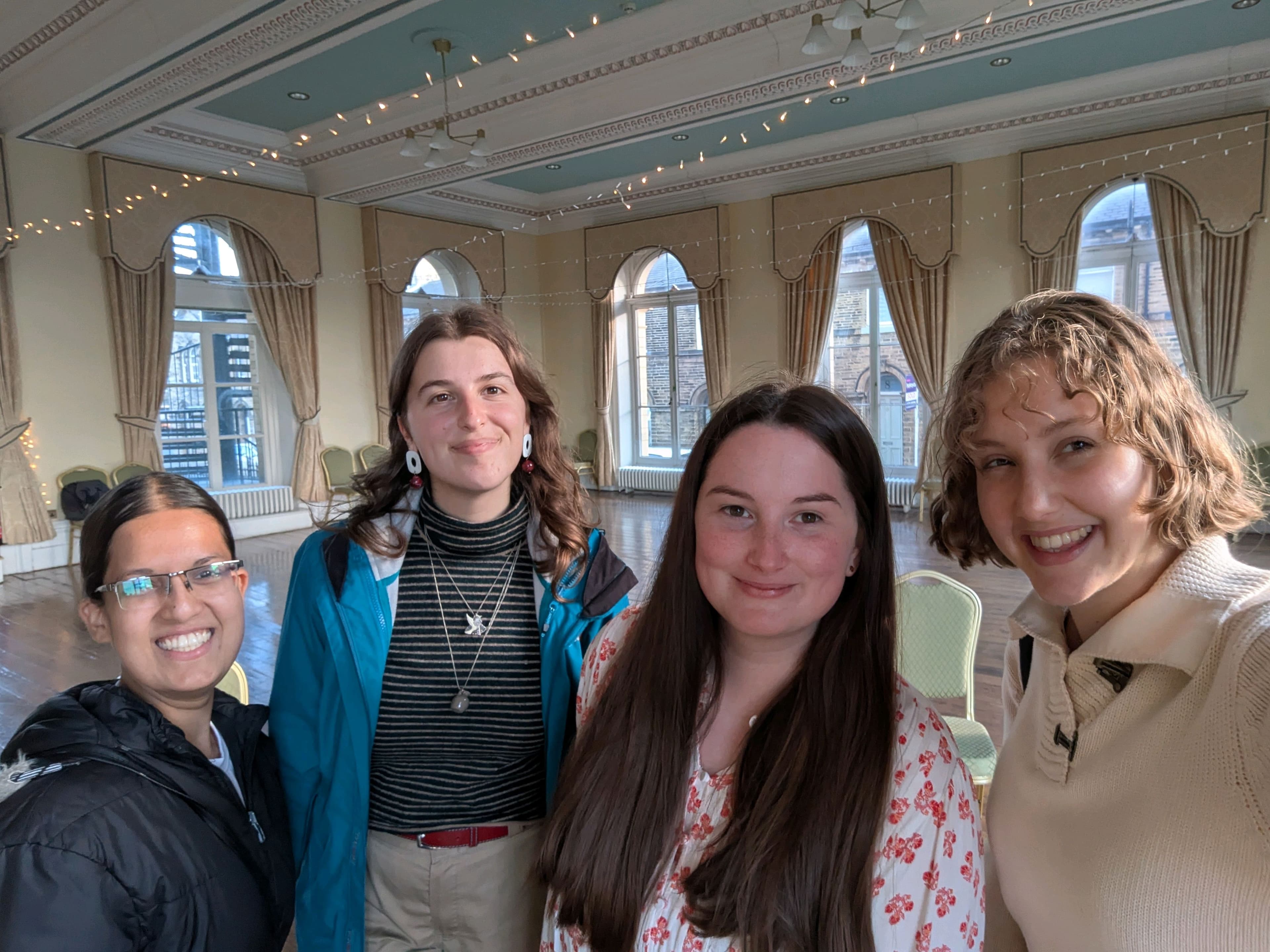 Four young women stand in a line and smile at the camera.