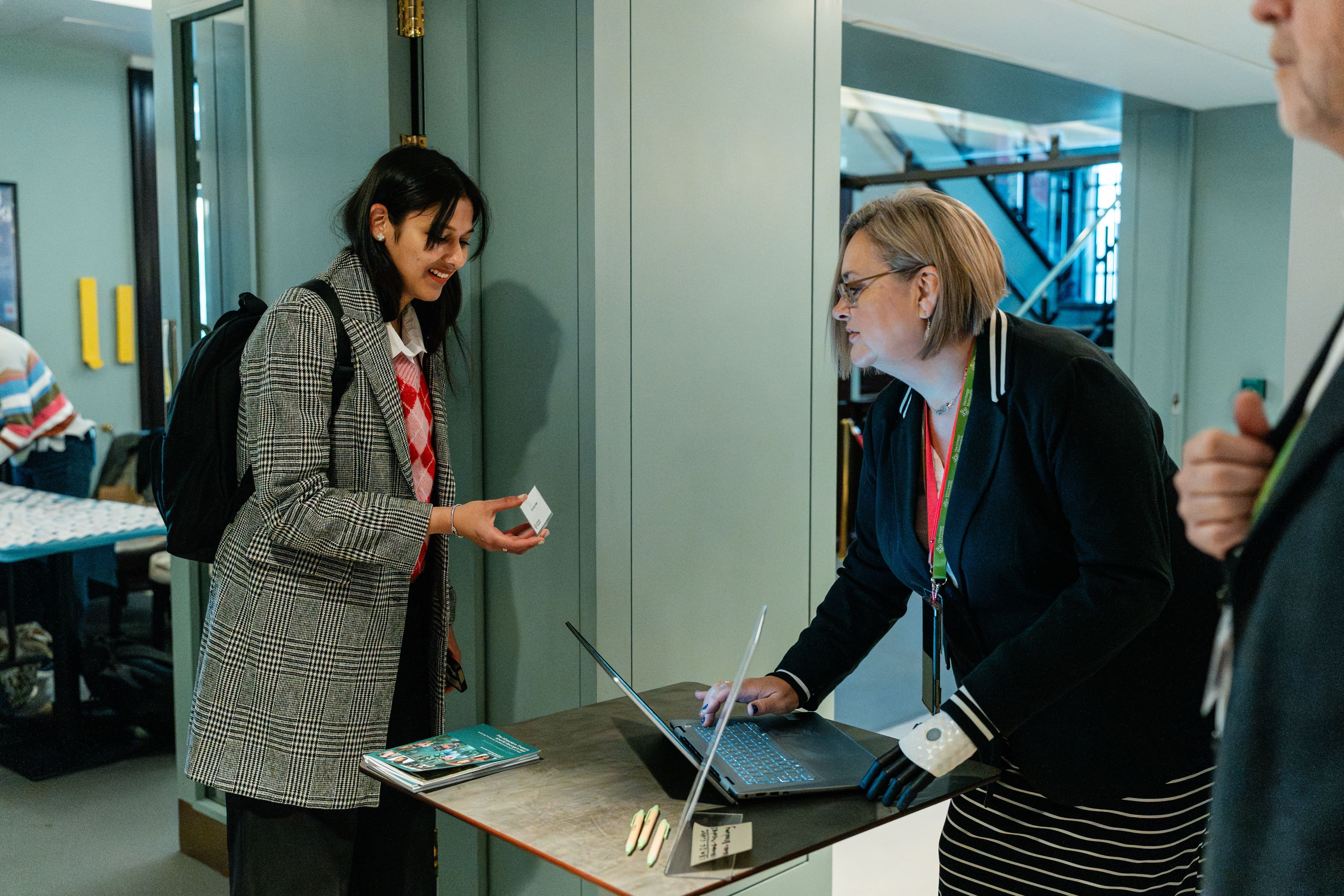 A lady with a laptop checks the ID of another lady.